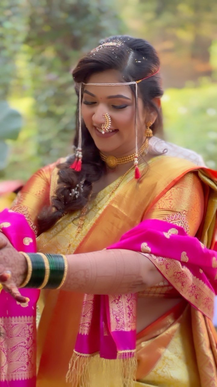 Maharashtrian bride in a gold Paithani saree with a pink dupatta and green bangles at Fort JadhavGadh, Pune, bridal makeup by Tejaswini Gote
