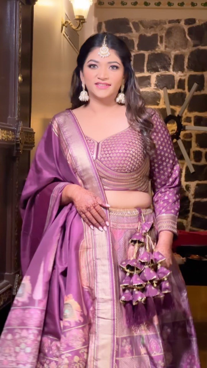 Close bridal portrait in a lilac Banarasi lehenga against the fort stonework at Fort JadhavGadh, makeup and hairstyling by Tejaswini Gote